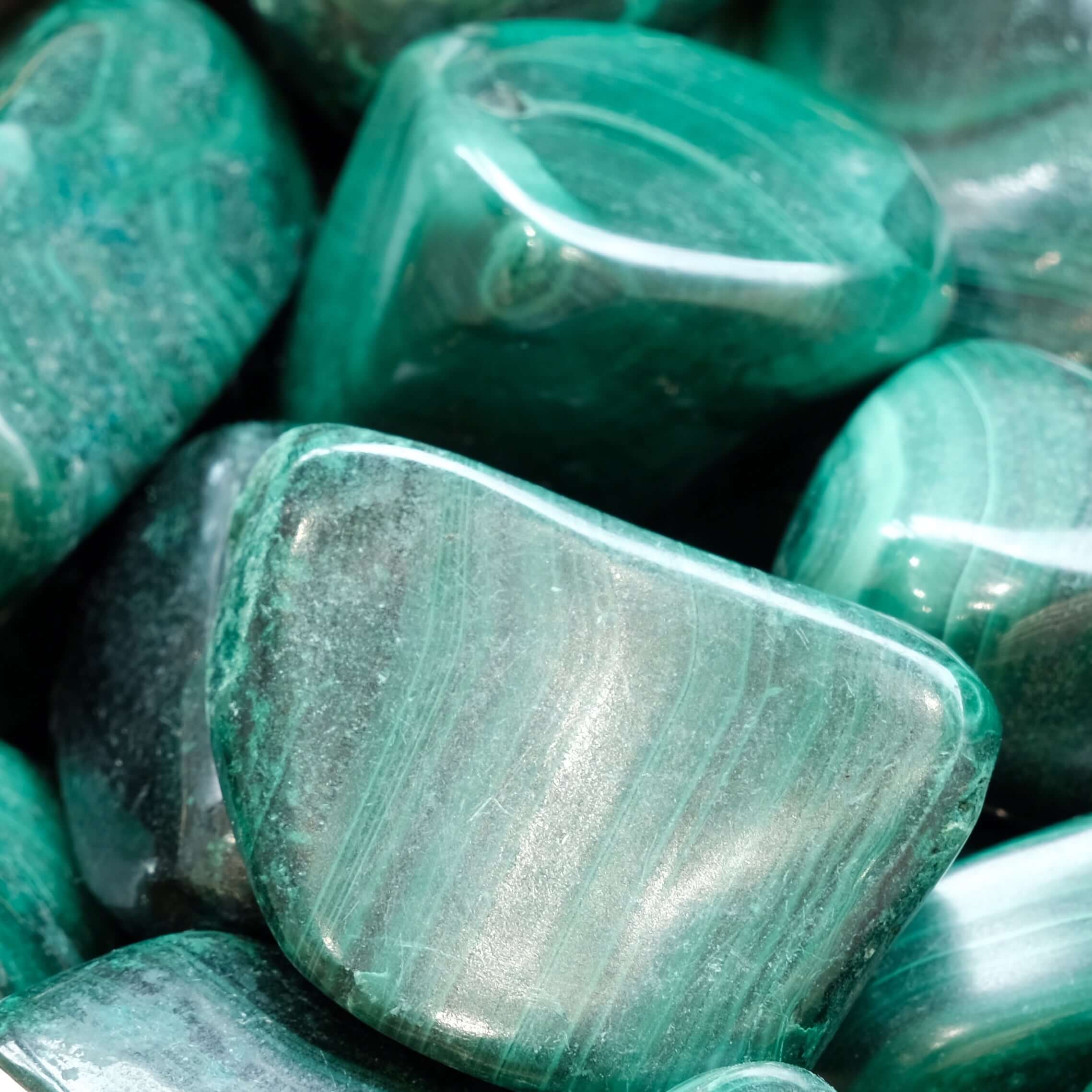 Close-up of polished malachite tumbled stones showcasing rich green hues and smooth textures, ideal for energy healing.