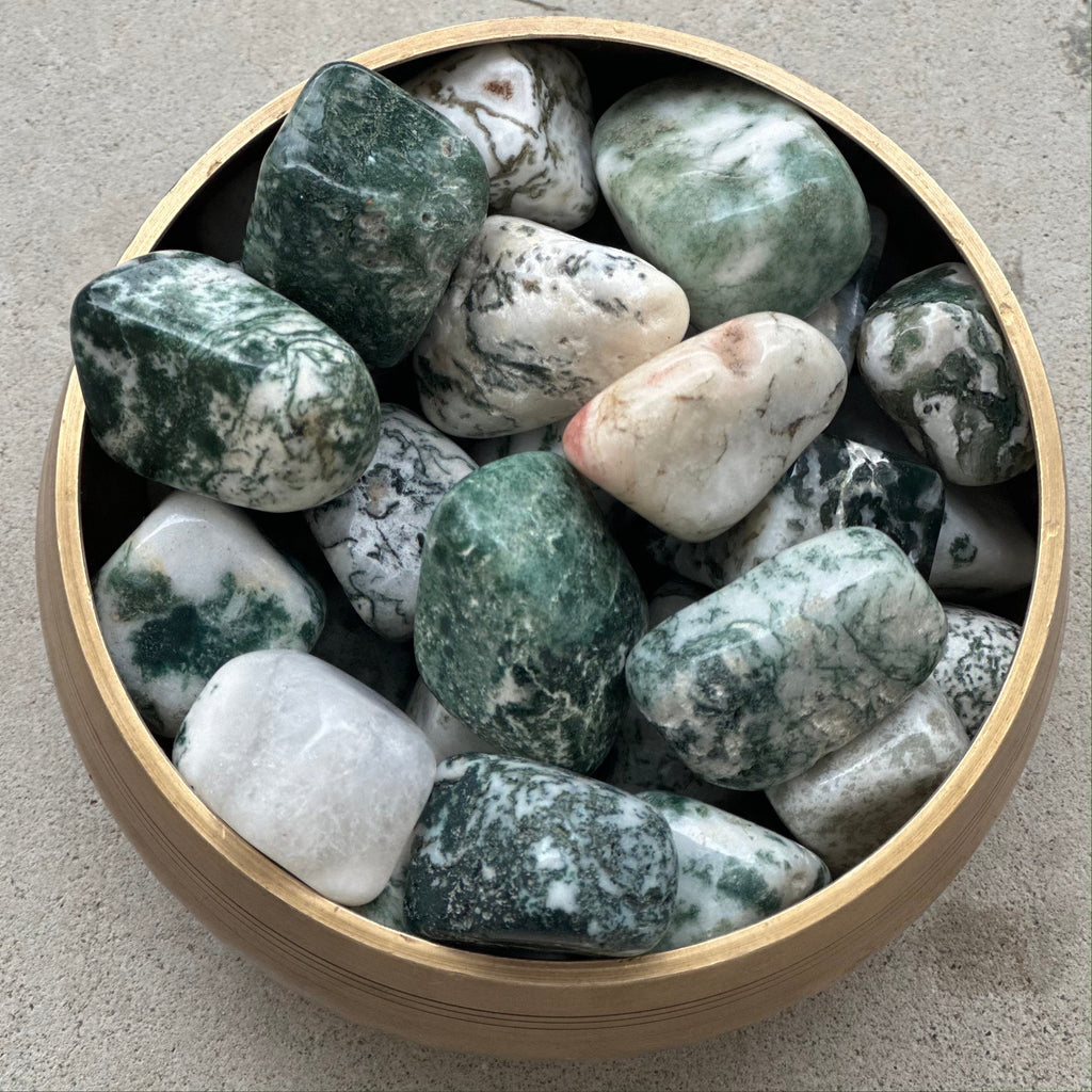 Bowl of tumbled moss agate stones with green and white patterns, known for healing properties and emotional balance.